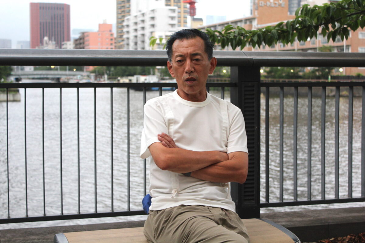 腕を組みながらインタビューに答える山田ゴメスさんの画像
