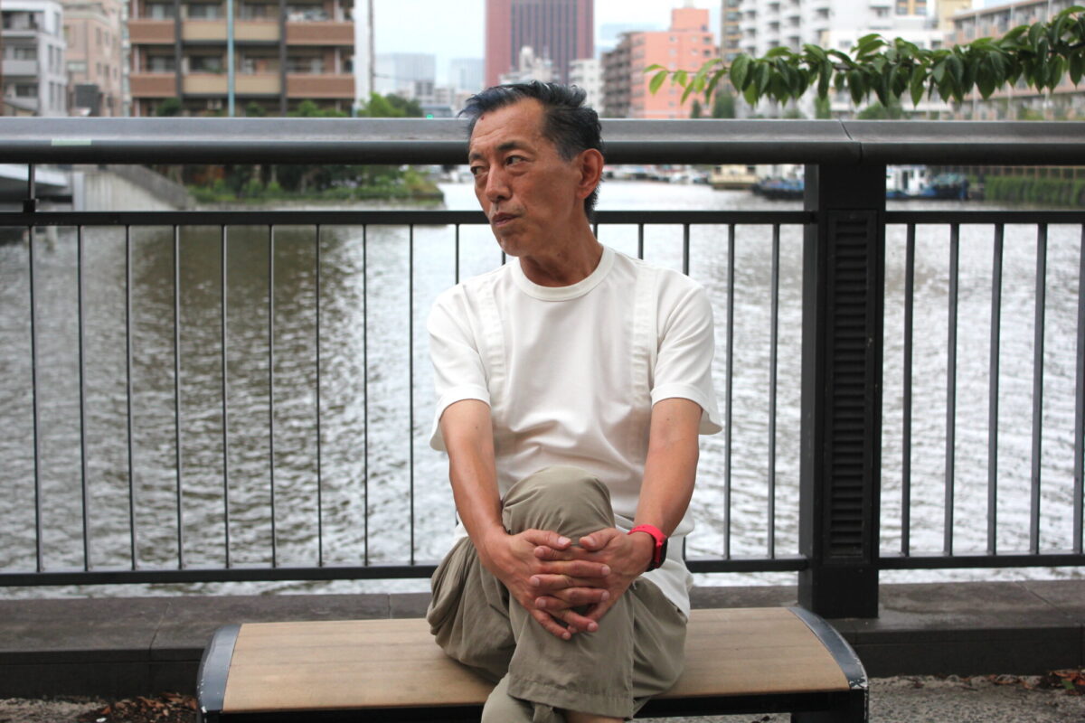 ベンチに座ってインタビューに答える山田ゴメスさんの画像